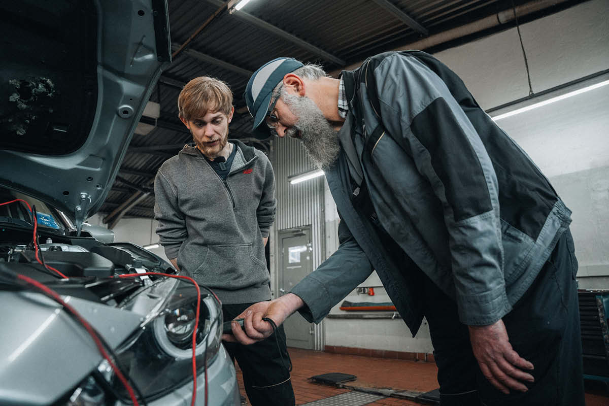Zwei Mechaniker machen Inspektion im Auto in einer Werkstatt